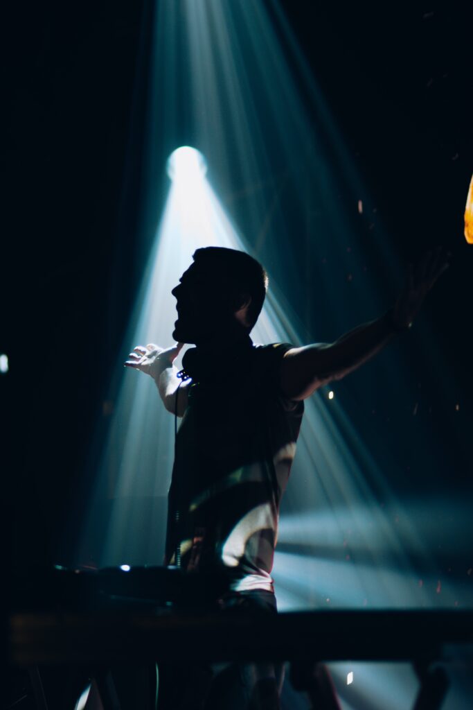 A dj in silhouette with his arms up in the air